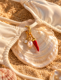 Charm Piment Péi – piment rouge, perle et strass sur un bikini blanc posé dans un coquillage nacré