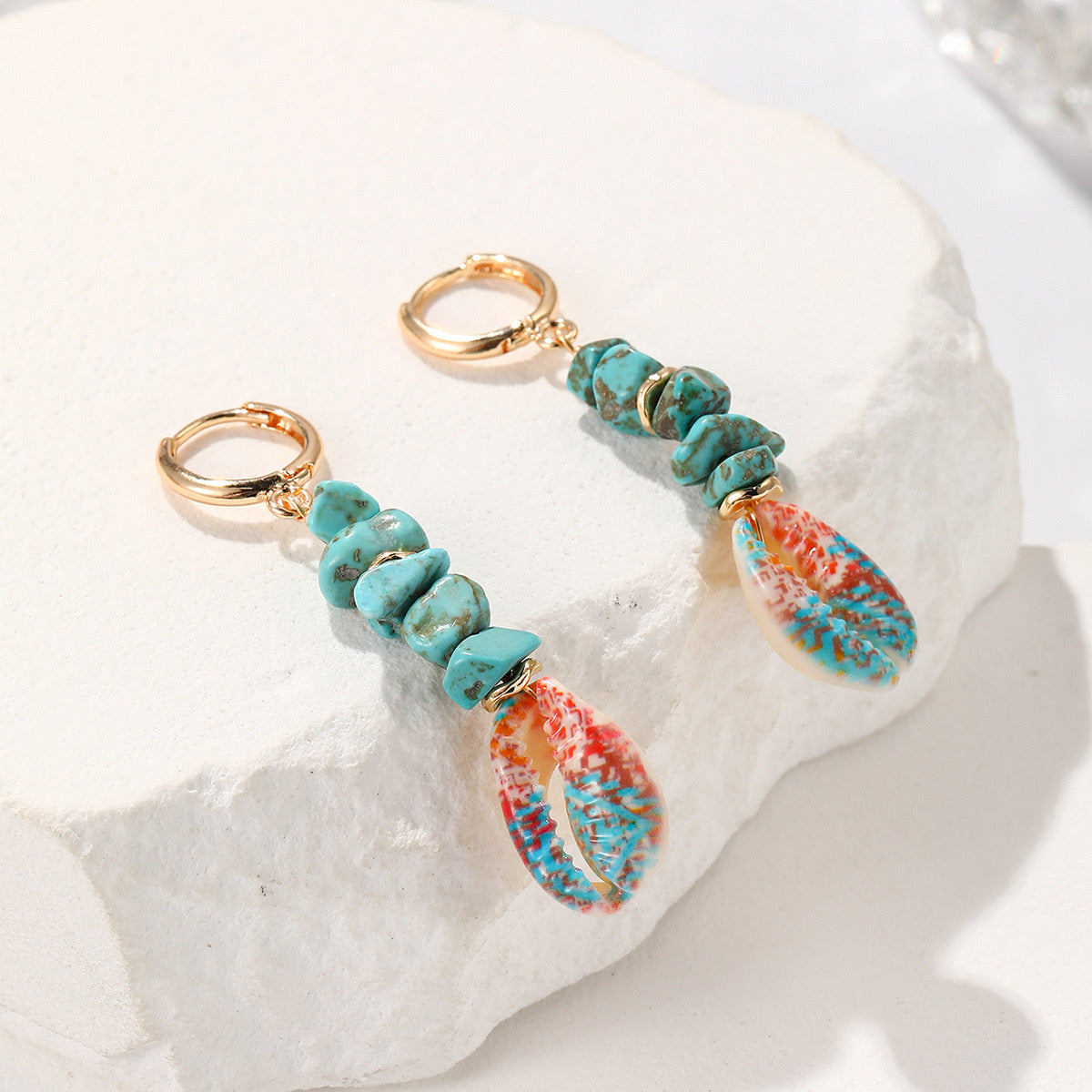 Charm Coquillage Lagon bleu – deux charms turquoise et cauri peint posés sur une pierre blanche